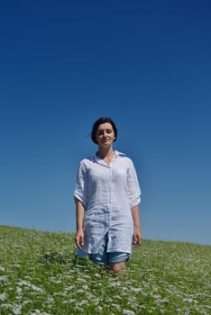 Young happy woman in green field with blue sky in background