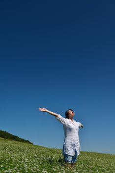 Young happy woman in green field with blue sky in background