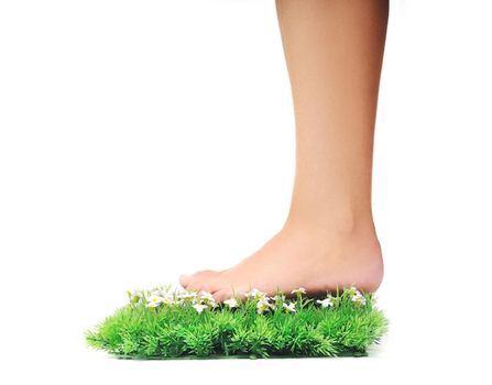 woman legs walking on small peace of green grass isolated on white representing last oasis concept