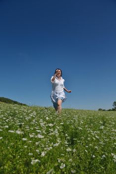 Young happy woman in green field with blue sky in background