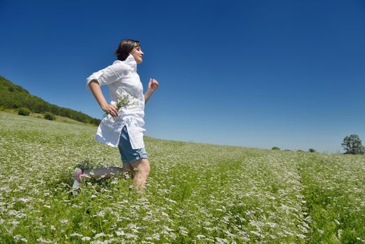 Young happy woman in green field with blue sky in background