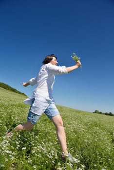 Young happy woman in green field with blue sky in background