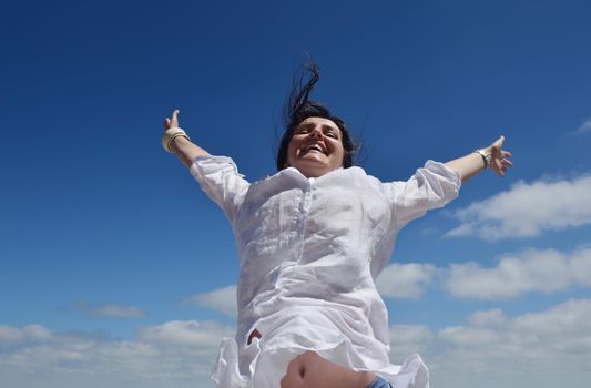 Happy  young woman with spreading arms, blue sky with clouds in background  - copyspace