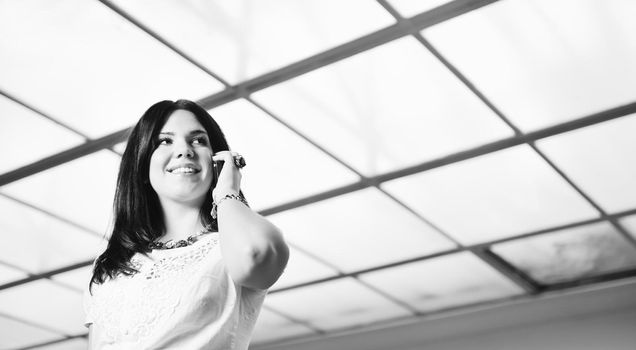 one young happy business woman talking by cellphone indoor in bright building