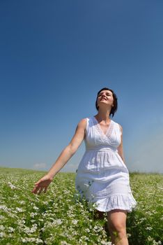 Young happy woman in green field with blue sky in background