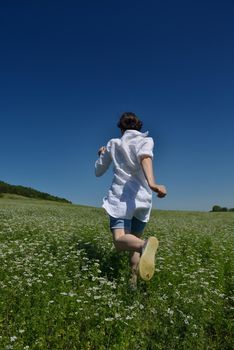 Young happy woman in green field with blue sky in background