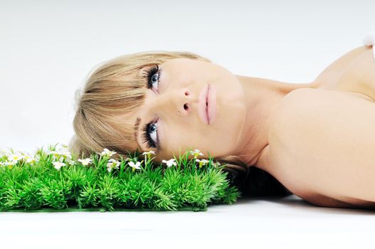 beautiful blonde woman face isolated on white with small green peace of grass