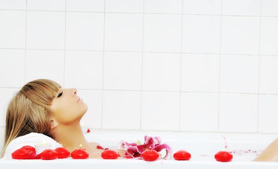 woman beauty spa and wellness treathment with red flower petals in bath