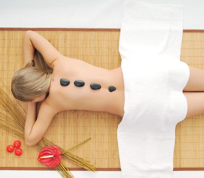 young healthy woman in wellness and spa studio have Massage with hot volcanic stones