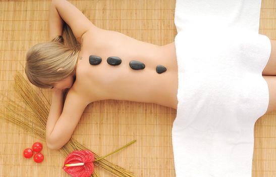 young healthy woman in wellness and spa studio have Massage with hot volcanic stones