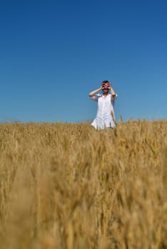 Young woman standing jumping and running  on a wheat field with blue sky the background at summer day representing healthy life and agriculture concept