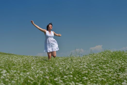 Young happy woman in green field with blue sky in background