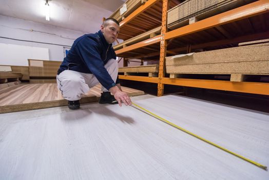 young man carpenter measuring wooden board for cutting while working in big modern carpentry High quality wood concept