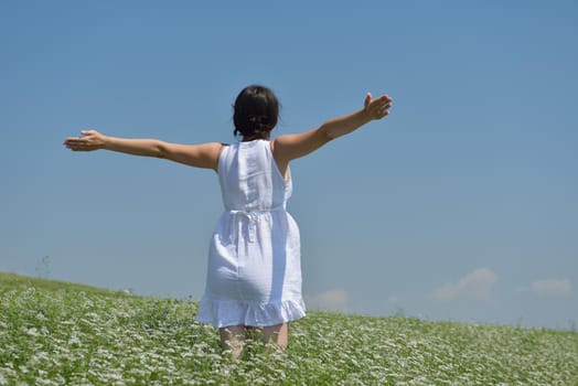 Young happy woman in green field with blue sky in background