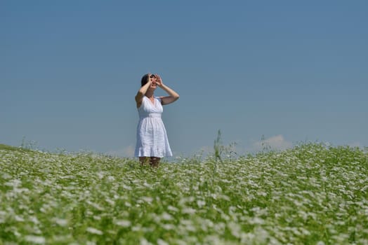 Young happy woman in green field with blue sky in background