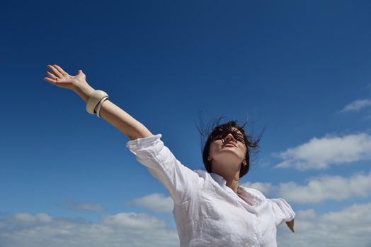 Happy  young woman with spreading arms, blue sky with clouds in background  - copyspace