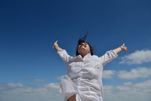 Happy  young woman with spreading arms, blue sky with clouds in background  - copyspace