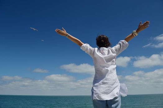 Happy  young woman with spreading arms, blue sky with clouds in background  - copyspace