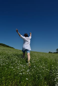 Young happy woman in green field with blue sky in background