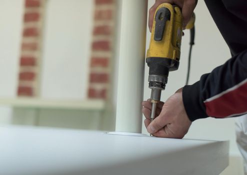 repairman working with drilling machine and assambling  furniture