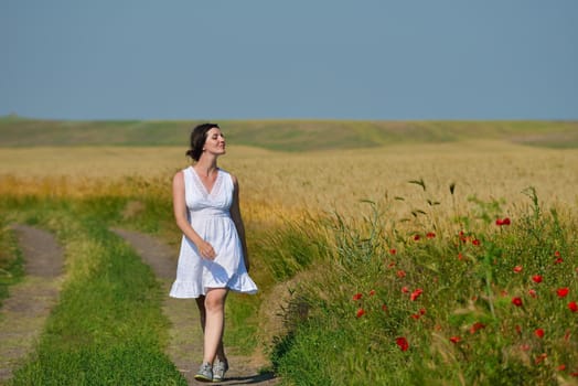 Young happy woman in green field with blue sky in background