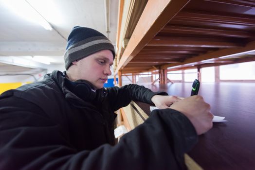 young man carpenter using pen while writing a receipt  in big modern carpentry