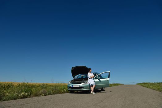 portrait of young beautiful woman with broken car outdoor