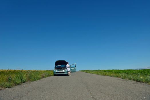 portrait of young beautiful woman with broken car