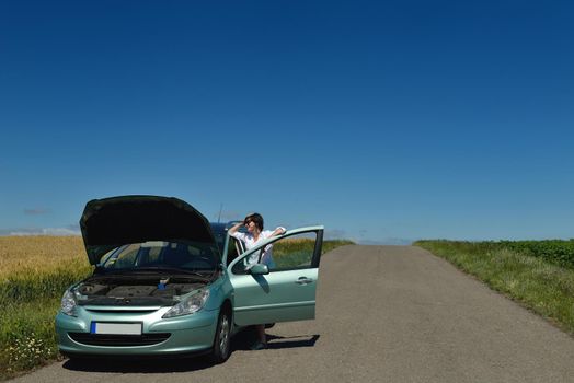 portrait of young beautiful woman with broken car outdoor