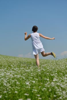 Young happy woman in green field with blue sky in background