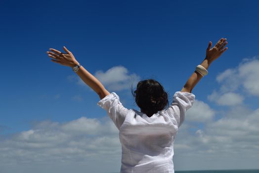 Happy  young woman with spreading arms, blue sky with clouds in background  - copyspace