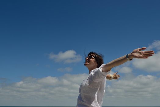 Happy  young woman with spreading arms, blue sky with clouds in background  - copyspace