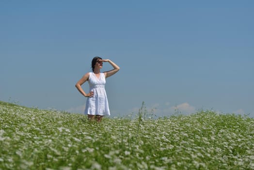 Young happy woman in green field with blue sky in background