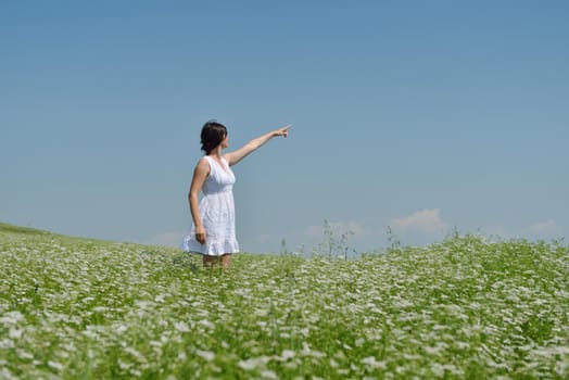 Young happy woman in green field with blue sky in background