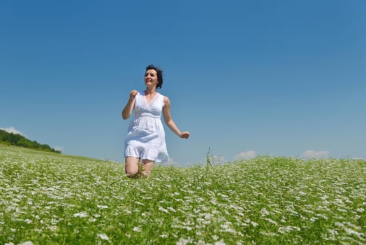 Young happy woman in green field with blue sky in background