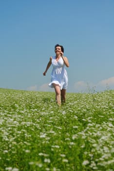 Young happy woman in green field with blue sky in background