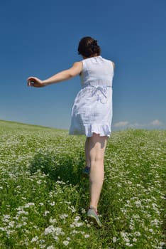 Young happy woman in green field with blue sky in background