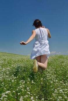 Young happy woman in green field with blue sky in background