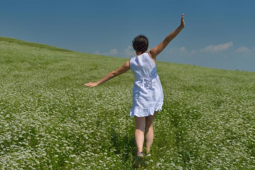 Young happy woman in green field with blue sky in background