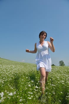 Young happy woman in green field with blue sky in background