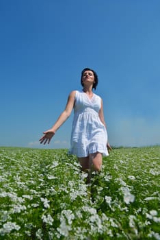 Young happy woman in green field with blue sky in background