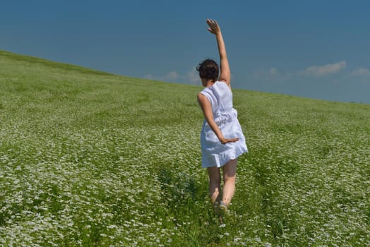 Young happy woman in green field with blue sky in background