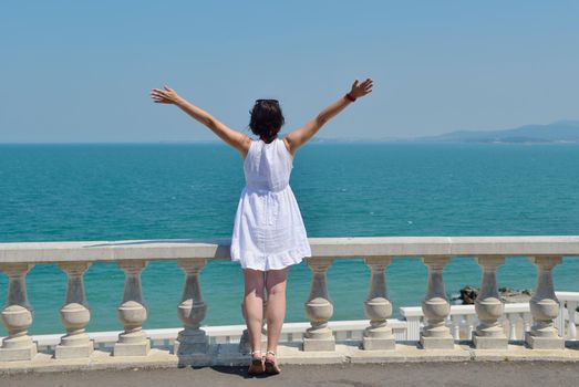 Happy  young woman with spreading arms, blue sky with clouds in background  - copyspace