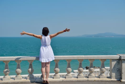 Happy  young woman with spreading arms, blue sky with clouds in background  - copyspace