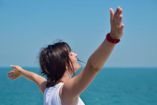 Happy  young woman with spreading arms, blue sky with clouds in background  - copyspace