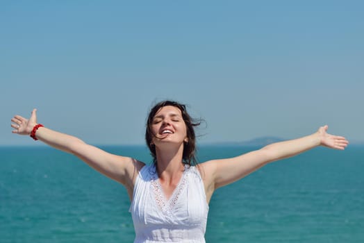 Happy  young woman with spreading arms, blue sky with clouds in background  - copyspace