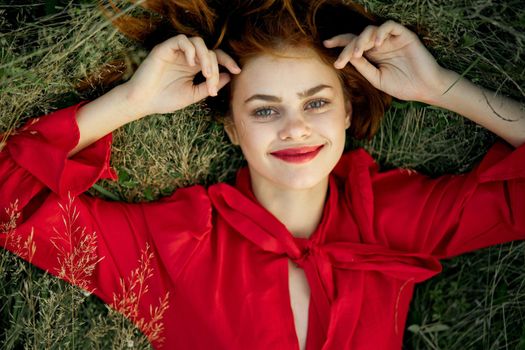 woman in red dress lies on the grass top view freedom. High quality photo