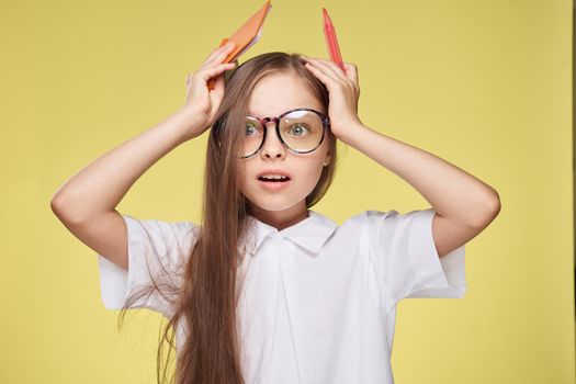 schoolgirl with textbook in hands learning childhood yellow background. High quality photo