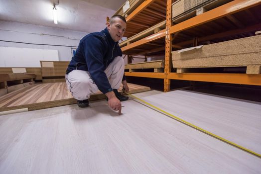 young man carpenter measuring wooden board for cutting while working in big modern carpentry High quality wood concept