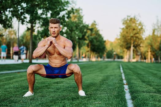 athletic man with a pumped up body in the park exercise fitness. High quality photo